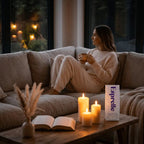 Woman sitting on a couch holding a mug of Esprelle decaf coffee in a cozy living room with candles and a book.