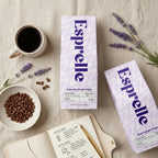 Esprelle coffee boxes with coffee beans, a cup of coffee, and lavender on a textured surface.
